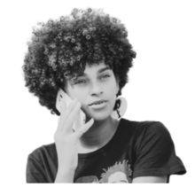 Young person with curly haired styled in an afro. They are wearing a black t-shirt and are holding a smart phone to their ear as if they are talking on the phone.